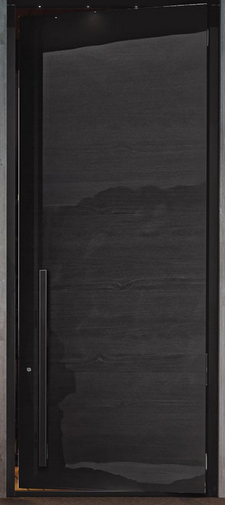A nearly black door fills a tall dark frame in a close, front-facing view. The broad door face has subtle horizontal wood-like texture and a long narrow pull handle along the left side. Small bright gaps and narrow brown-toned edges are visible around parts of the frame.