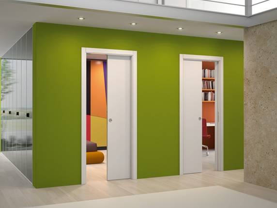 Two white sliding doors are set into separate openings along a vivid lime-green wall. Both doors are partly open, revealing portions of rooms with shelves, seating, and warm-colored surfaces. Pale wood flooring, a glass partition at the left, and recessed ceiling lights are also visible.